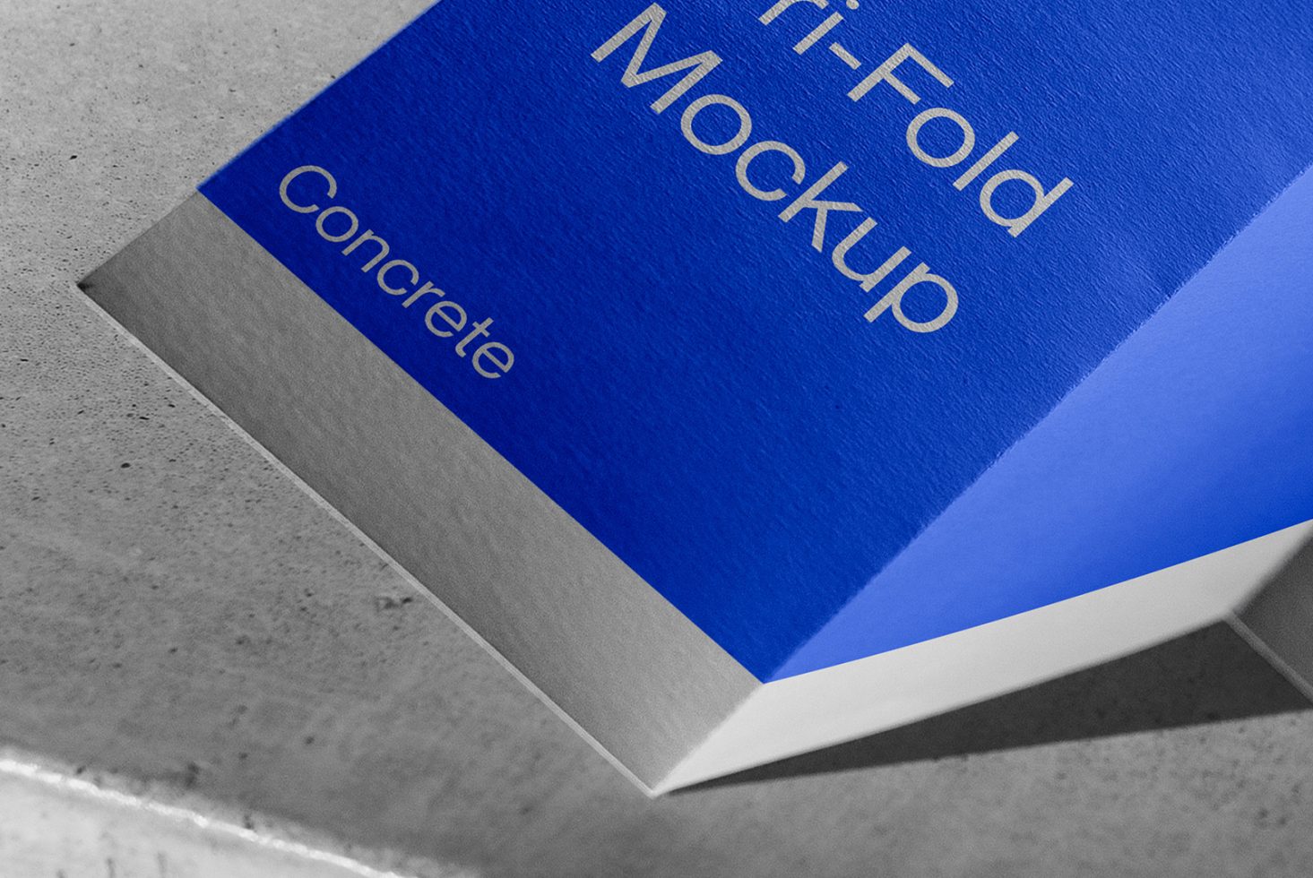 Blue and white tri-fold brochure mockup with concrete text, displayed on a textured surface, showcasing realistic shadows and design template.